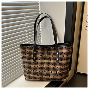 Close-up of heart pattern weave on a tote bag with leather logo and rivet details