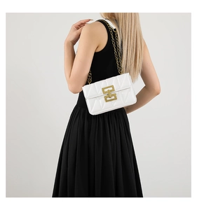 Détail du sac à chaîne blanc matelassé avec boucle dorée porté par un mannequin
