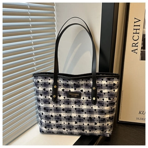 Detail of blue and white checkered tote bag with black heart prints and leather handles