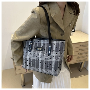 Sac fourre-tout à carreaux avec anses en cuir porté par un mannequin en blazer