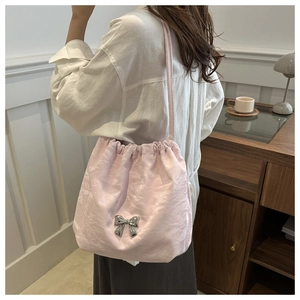 Détail d'un sac seau en satin rose avec nceud argenté porté par un mannequin