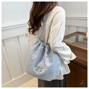 Detail of light blue drawstring tote bag with textured fabric and silver bow charm