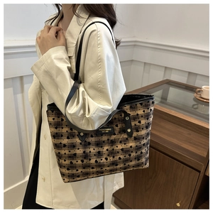 Detail of vintage tote bag with heart-print plaid fabric and gold rivet accents