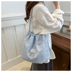 Vue détaillée du sac à cordon bleu clair avec nœud argenté et texture plissée