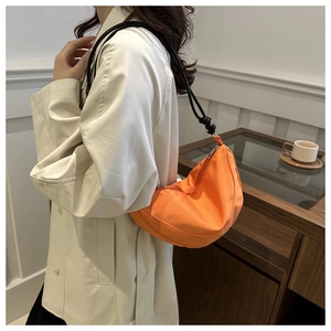 Modelo con bolso de media luna naranja vibrante y detalles de correa de cuerda negra
