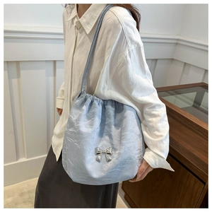 Detail of light blue drawstring bag featuring a metallic silver bow on crinkled fabric