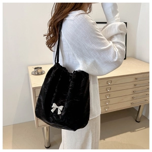Side view of a large black soft tote bag with drawstring and silver bow detail