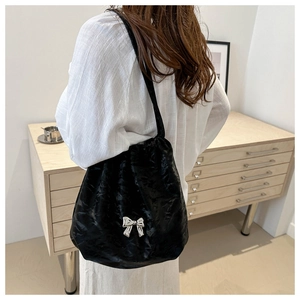 Détail d'un sac cabas plissé noir avec un nœud métallique argenté et fini satiné