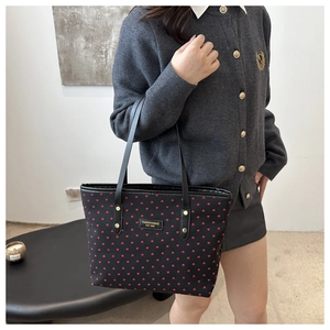 Détail du sac cabas noir à motifs de cœurs rouges porté par un mannequin