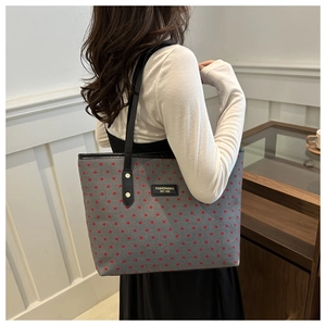 Détail du grand cabas gris à motifs de cœurs rouges avec finitions en cuir et logo