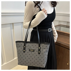 Detail of grey canvas tote bag with star prints, leather logo patch and metal rivets