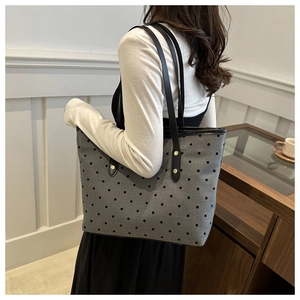 Polka dot tote bag detail showing grey fabric, black handles and gold rivet accents