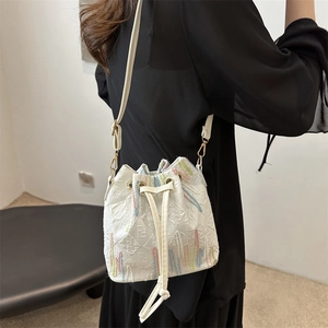 Chic white drawstring bucket bag with embossed logo texture and colorful wavy embroidery