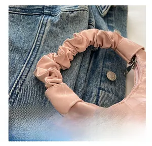 Vue détaillée de la poignée plissée rose du sac à main avec texture marbre et zip en métal