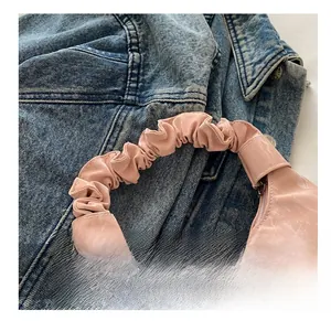 Détail du sac à main rose marbré avec poignée plissée sur fond en denim bleu