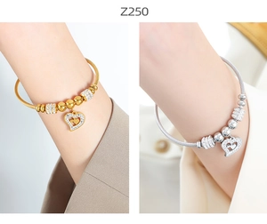 Detail of beaded steel cable bracelets with heart pendants in gold and silver finish