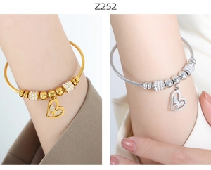 Detail of twisted cable heart bracelet in gold and silver finish with zircon charms