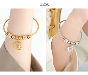 Close-up of gold and silver wire cable bracelets with heart and star charms on wrist