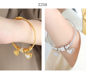 Detail of twisted cable bangles in gold and silver with zircon-encrusted heart pendants