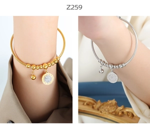 Detail of gold and silver cable bracelets with zircon charms and beads on wrist