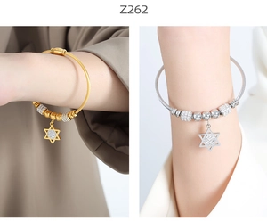 Detail of gold and silver cable bracelets with star pendants on model's wrist