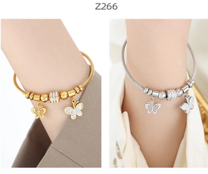 Detail of gold and silver steel cable bangles with sparkling zircon butterfly charms