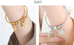 Detail of twisted cable bangles in gold and silver with clover charms and zircons