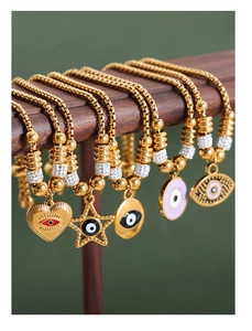 Detailed set of gold evil eye charms including heart and star shapes on beaded bracelets