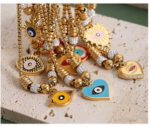 Close-up of golden evil eye bracelets with colorful enamel hearts and sun charms