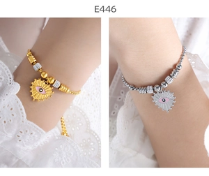Detail of pink enamel devil eye heart charms on gold and silver beaded bracelets