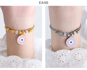 Detail of beaded evil eye charm bracelets in gold and silver finish on wrist