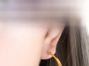 Gros plan d'un mannequin portant de grandes créoles dorées au style minimaliste