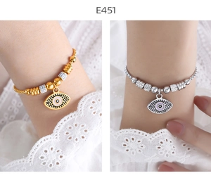 Detail of gold and silver Evil Eye bracelets with blue charms and zircons on a wrist
