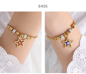 Detail of gold beaded bracelets with evil eye star charms and sparkling white crystals