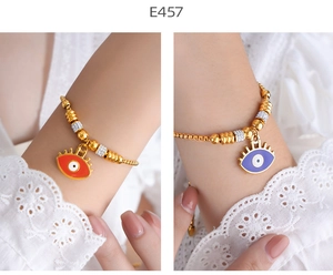 Close-up of gold beaded bracelets with red and purple enamel evil eye heart charms