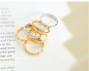 Close-up of six minimalist gold and silver bamboo shaped titanium steel rings on a book