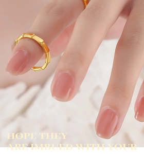 Detailed view of a gold bamboo-style titanium steel ring worn on the index finger