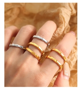 Close-up of stacked gold and silver bamboo style titanium rings on model fingers