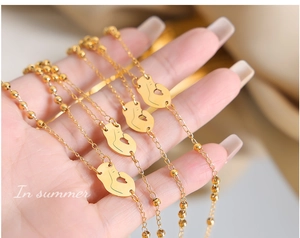 Detailed close-up of golden layered necklaces with mother-and-child pendant held by hand
