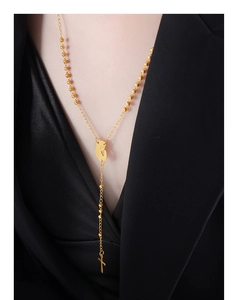Detail of gold-plated Y-necklace with cross pendant and beads on a chic black blazer