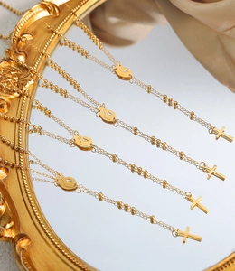 Detail of four golden cross and cat necklaces on vintage mirror with silk background