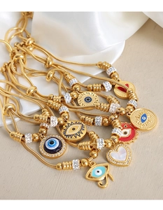 Detalle de pulseras de cadena de serpiente doradas ajustables con dijes de ojo y corazón