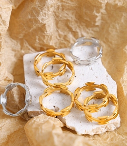Dettaglio di anelli intrecciati in oro e argento su espositore in pietra bianca