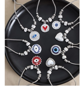 Detalle de cadenas de serpiente plateadas con dijes de ojo turco y colgantes de corazón