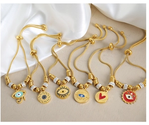 Detalle de pulseras ajustables de ojo turco dorado con circonitas y colgantes de corazón