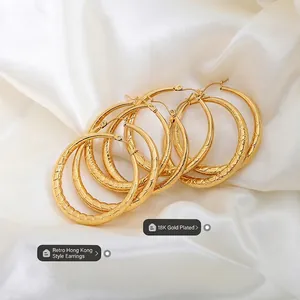 Grandes créoles rétro plaquées or 18 carats avec texture sur fond de soie blanche
