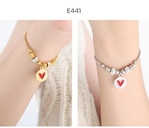 Detalle de pulseras de corazón oro y plata con circonitas y colgantes de esmalte rojo