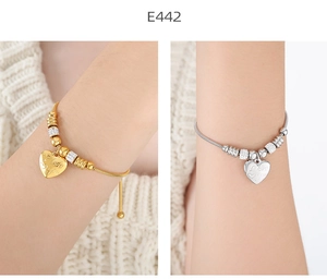 Detalle macro de pulseras de serpiente en oro y plata con colgantes de corazón grabado