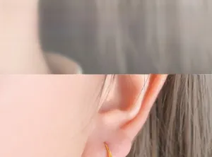 Détail de breloques cœur dorées sur boucles d'oreilles perles portées
