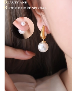 Gros plan sur boucle d'oreille goutte dorée avec perle ronde sur un modèle féminin